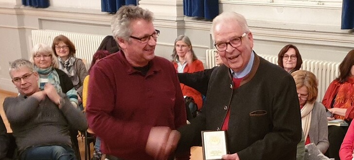 Der künstlerische Leiter Helgo Hahn (links) überreicht dem Chorvereins-Vorsitzenden Hans Jürgen Dietz für 50 Jahre verdienstvolle Jahre eine Ehrenplakette