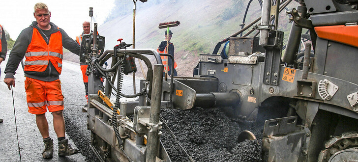 Der Asphalt wird auf die Straße durch den Fertiger aufgetragen. Um so genau wie möglich zu arbeiten, wird moderne Technik verwendet.