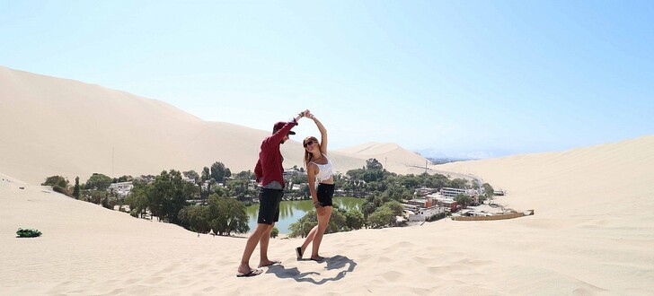 Zeit zum Tanzen: Anni und Thommy vor der Oase „Laguna de Huacachina" in der peruanischen Stadt Ica