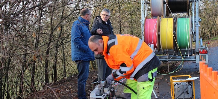 Gleich sieben Kabel werden am Stadtrand von Ulrichstein mit Druckluft in ein Leerrohr geblasen. Durch eine der bunten Röhren wird dann das Glasfaserkabel nach Feldkrücken führen, denn „Schritt für Schritt werden auch die kleinen Dörfer im Vogelsbergkreis mit schnellem Internet versorgt“, betont Landrat Manfred Görig beim Besuch auf der Baustelle.