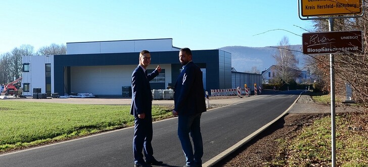 Geschäftsführer Alexander August (rechts) zeigt Bürgermeister Andre Stenda deren neue Fertigungshalle mit Büroareal am Ortsrand von Oberbreitzbach.